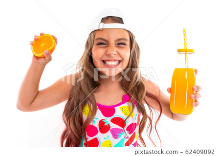 tanned girl squeezes an orange and holds a glass of juice on a white background 62409092