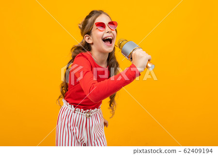 young singer with a microphone in her hands on a yellow studio background with copy space young singer with a microphone in her hands on a yellow studio background with copy space 62409194