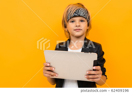 Stylish young boy in black jacket and white t-shirt serfing internet with his tablet Stylish young boy in black jacket and white t-shirt serfing internet with his tablet 62409196