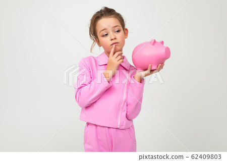 finance. portrait of a girl in a pink suit holding a money jar on a white background with copy space 62409803