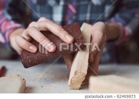 Carpenter hands polishing wooden planks with a 62409873