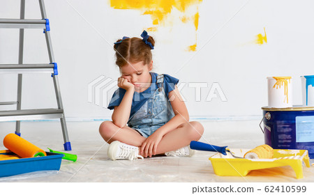 Repair in apartment. Tired child girl paints wall Repair in apartment. Tired child girl paints wall 62410599