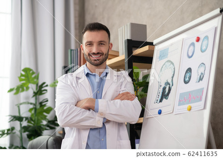 Young bearded doctor in a white robe looking positive 62411635