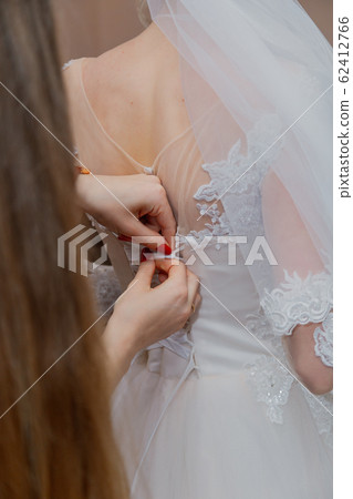 A young bride buttoned wedding dress. Happy A young bride buttoned wedding dress. Happy 62412766