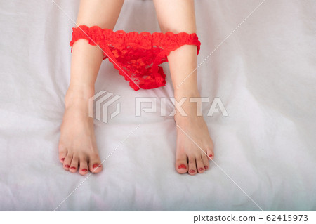 Beautiful leg sexy woman and reclines on the bed with black g-string between feet 62415973