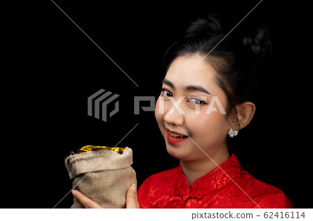 Portrait Asian young woman red dress traditional cheongsam holding a gold coin in a sack at the black background Portrait Asian young woman red dress traditional cheongsam holding a gold coin in a sack at the black background 62416114