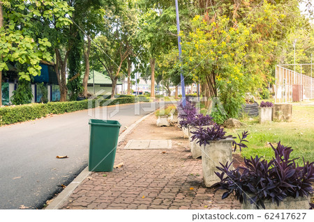 An old green dustbin in the public park beside the walk way for protect environment. An old green dustbin in the public park beside the walk way for protect environment. 62417627