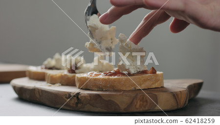 Slow motion man add ricotta to slice of ciabatta with fig marmalade and pancetta Slow motion man add ricotta to slice of ciabatta with fig marmalade and pancetta 62418259