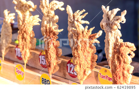 Large fried Japanese squid fried on skewers for sale in street food in Thailand. Large fried Japanese squid fried on skewers for sale in street food in Thailand. 62419895