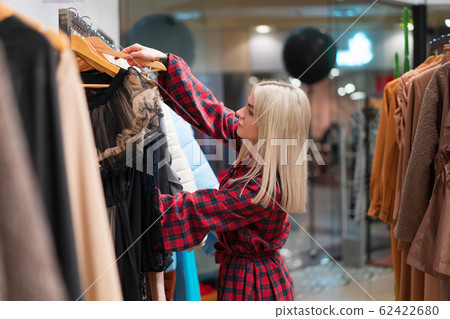 One caucasian women in a fashion boutique choose clothes buy for autumn season. One caucasian women in a fashion boutique choose clothes buy for autumn season. 62422680