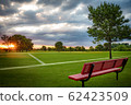Outdoor Soccer European football sports field during sunrise with a red bench and beautiful clouds 62423509
