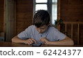 funny boy sits at a table at home and uses a phone, plays game 62424377