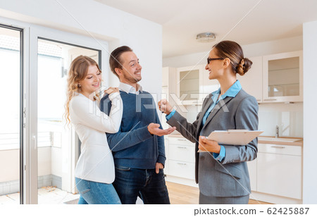 Realtor giving house key to the buyers or tenants Realtor giving house key to the buyers or tenants 62425887