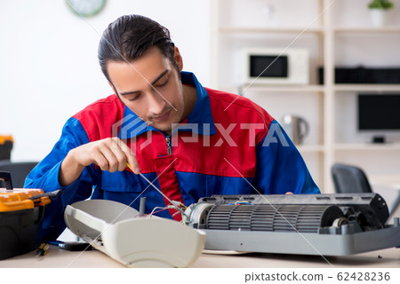 Young repairman repairing air-conditioner at warranty center Young repairman repairing air-conditioner at warranty center 62428236