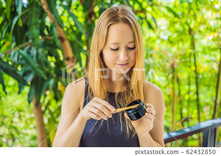 Young woman brush teeth using Activated charcoal powder for brushing and whitening teeth. Bamboo eco 62432850