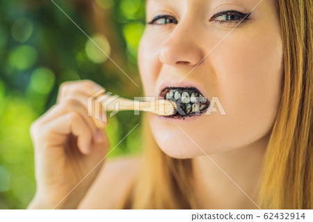 Young woman brush teeth using Activated charcoal powder for brushing and whitening teeth. Bamboo eco 62432914