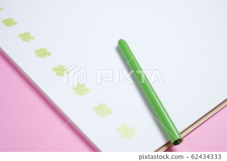 Sketchbook with yellow-green color pencil and four-leaf clover on pink background paper 62434333