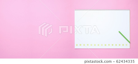 Sketchbook with yellow-green color pencil and four-leaf clover on pink background paper 62434335