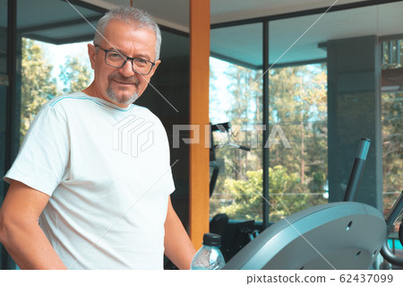 Mature man in the gym with a bottle of water exercises Mature man in the gym with a bottle of water exercises 62437099