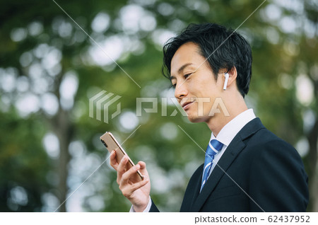Businessman wearing earphones 62437952