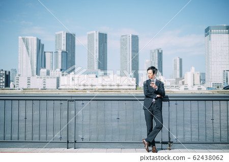 Businessman with smartphone outside 62438062