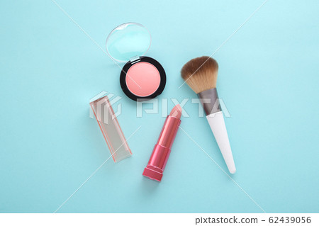 Pink lipstick, blush and brush on blue background Pink lipstick, blush and brush on blue background 62439056