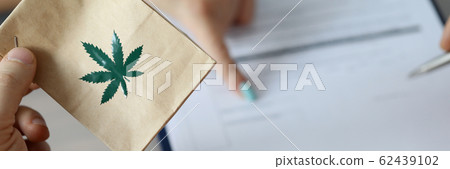 Male arm holding paper packet 62439102