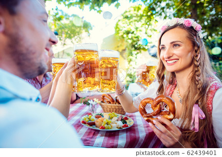 Couple clinking glasses with huge amounts of beer in Bavarian pub 62439401