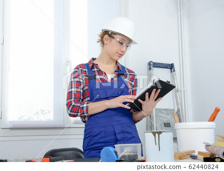 young woman with safety helmet, using a digital 62440824