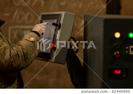 Worker using dashboard of CNC machinery Worker using dashboard of CNC machinery 62440999
