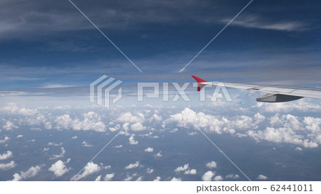 Plane travel concept : View from aircraft window. Clouds and blue sky under airplane wing as seen through window of an airplane in wide angel with copy space for travel agency background 62441011