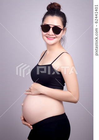 Happy mom concept : Portrait of happy pregnant Asian woman with smile face in black dress with sun glasses. Beautiful Asia female model in her 20s. 62441401