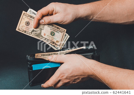 Leather wallet with money in male hands on dark Leather wallet with money in male hands on dark 62441641