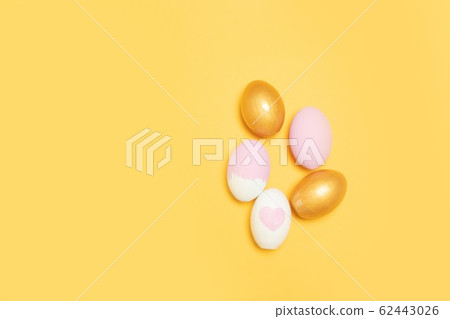 Top view of gold and pink easter eggs on yellow Top view of gold and pink easter eggs on yellow 62443026