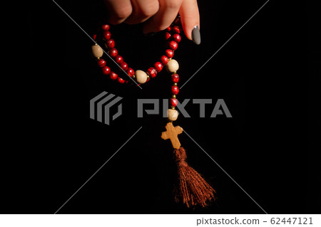 Close up of a woman's hand holding rosary beads. Close up of a woman's hand holding rosary beads. 62447121