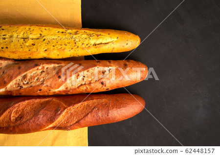 Three crispy french baguettes lie on an old wooden Three crispy french baguettes lie on an old wooden 62448157