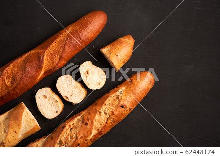Three crispy french baguettes lie on an old wooden Three crispy french baguettes lie on an old wooden 62448174