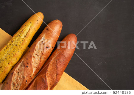 Three crispy french baguettes lie on an old wooden Three crispy french baguettes lie on an old wooden 62448186