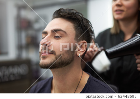 Handsome blue eyed man sitting in barber shop. Handsome blue eyed man sitting in barber shop. 62448693