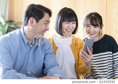 父母和孩子看著一個智能手機的圖像 62450592