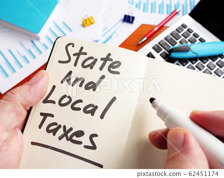 Man calculating State and Local Taxes in the note. Man calculating State and Local Taxes in the note. 62451174