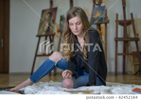 Portrait of a woman artist sitting on the floor Portrait of a woman artist sitting on the floor 62452164