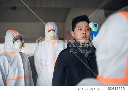 People with protective suits helping man outdoors, coronavirus concept. People with protective suits helping man outdoors, coronavirus concept. 62453333