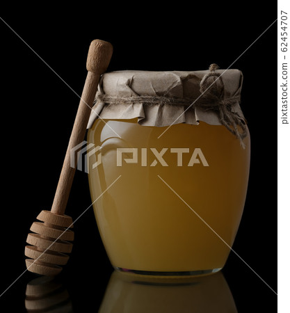 Sweet honey in jar with honey dipper on black background. Organic honey. Sweet honey in jar with honey dipper on black background. Organic honey. 62454707