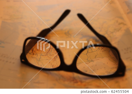 Pair of upturned glasses resting on a map with focus through lenses Pair of upturned glasses resting on a map with focus through lenses 62455504