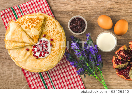 top view of traditional pancakes, jam, milk and square pattern napkin. delicious traditional dessert 62456340
