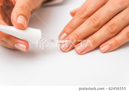 closeup beautiful female hands painting nails with transparent polish 62456355