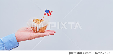 Cupcake with American flag on male palm against 62457492