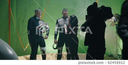 Director watching a shooting and discussing with an actor Director watching a shooting and discussing with an actor 62458912