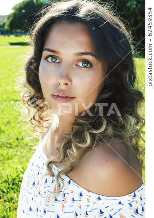 young cute adorable real summer girl on green grass outside relaxing smiling, lifestyle people concept 62459354